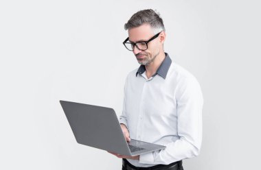 Gri arka planda bilgisayar üzerinde çalışan gözlüklü olgun işveren.