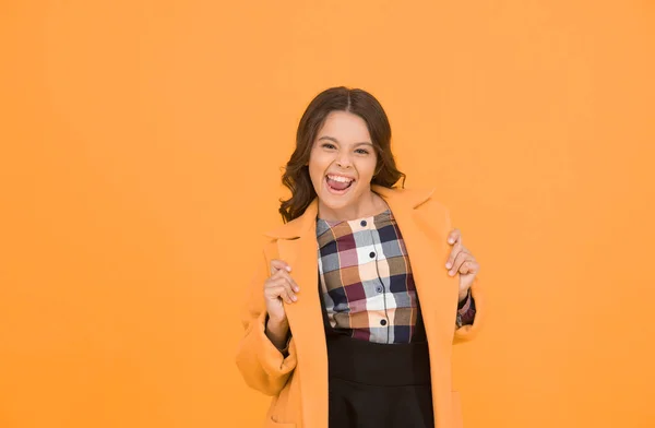 Yellow mood. Fancy child smiling face on yellow background. Yellow color. Girl fashionable cute model wear yellow wool coat. Personal styling and bespoke tailoring. Feeling cozy and comfortable.