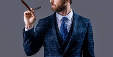man with blade in barber studio. photo of bearded man with barber blade. barber man hold blade isolated on grey background. barber man with razor blade.