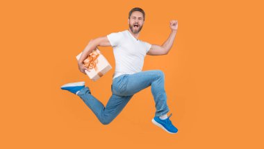 Şu anki kurye, havadaki sarı stüdyo arka planında. Aktif adam hediye kutusuyla hızlı koşuyor. Hediye ve hediye..