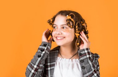 Güzel bir saç stili yap. Harika bir saç stili. Mutlu çocuk. Kuaför salonu. Mükemmel güzellik. Sarı arka planda saç tokası ve saç tokası olan bir kız. Saçlarının etrafında kıvırcık kızlar.