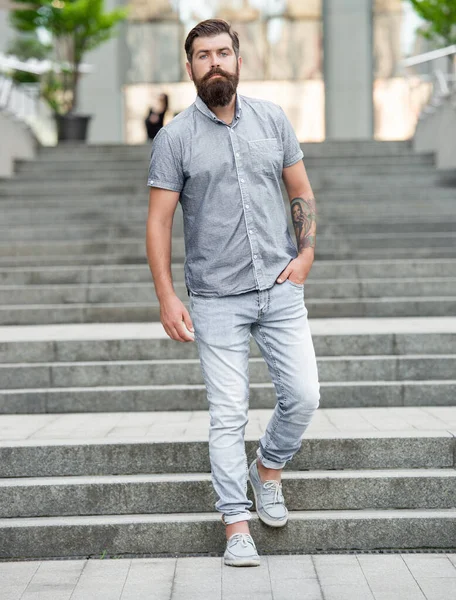 bearded hipster walking downstairs. full length of hipster with beard. caucasian hipster outdoor.