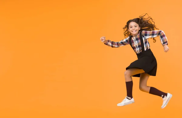 Happy childrens day. Jump concept. Break into. Feel inner energy. Girl with long hair jumping on yellow background. Carefree kid summer holiday. Time for fun. Active girl feel freedom. Fun and jump.