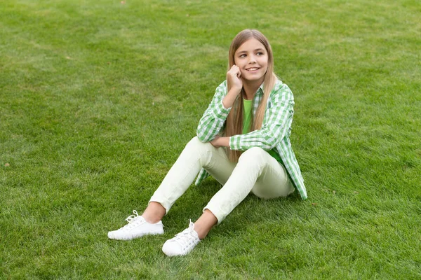 photo of thoughtful teen girl relax enjoying grass. teen girl relax on grass outdoor. teen girl relax on green grass. teen girl relax outside.