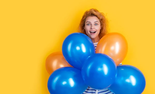 happy girl hold party balloons in studio. shocked girl with balloon for party isolated on yellow background. party girl with balloon.