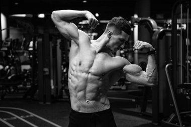 Formda, kaslı, kaslı, kaslı, spor salonunda çift kol pozu veren güçlü bir adam..