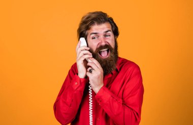 İletişim. Sakallı adam kırmızı gömlek giyer. Sıradan bir erkek telefonu. Sohbet konsepti. Adam sekreter ya da asistan retro telefonda konuşuyor. Telefonlu acımasız adam..