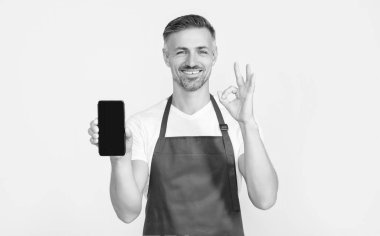 Önlüklü mutlu olgun bir adam akıllı telefona fotokopi alanı sunuyor. Tamam.