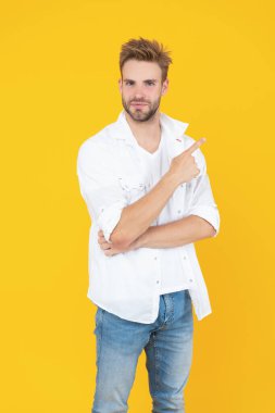 handsome man with stubble in studio, point finger. handsome man with stubble on background. photo of handsome man with stubble hair. handsome man with stubble isolated on yellow.