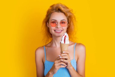 glad woman with cone icecream on background. photo of woman with cone icecream at summer. woman with cone icecream isolated on yellow. woman with cone icecream in studio.