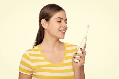 Beyaz arka planda elektrikli diş fırçası olan pozitif kız.