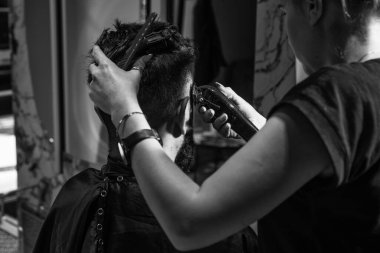 Adam, berber dükkanında saç kesiminde siyah saçlı, beyaz tenli bir tip..