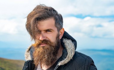 face of brutal man has beard. brutal man having moustache. photo of brutal man in the mountain. brutal man outdoor.