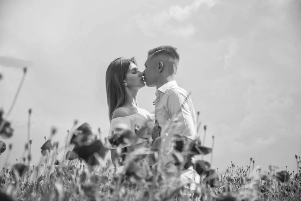 couple in love of man and woman kissing in summer poppy flower field, kiss.