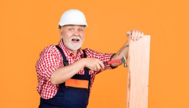 Sarı arka planda, miğferli kıdemli marangoz.