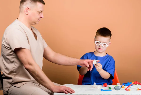 First aid. Medical help. Trauma and injurie. Medicine concept. Kid little doctor sit table medical tools. Health care. Medical examination. Boy cute child and his father doctor. Hospital worker.