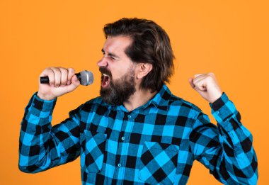 Kareli gömlekli vahşi adamın mikrofon ve karaokeyle uzun sakalı var..