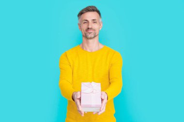 Stüdyoda alışveriş yapan adam gülümsüyor. Arkadan alışveriş yapan adam. Erkek alışverişçinin hediyesi. Hediye alan adam mavi üzerine izole edilmiş..