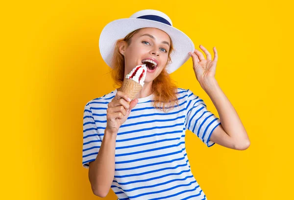 stock image photo of summer girl eat cone icecream in retro hat. summer girl with cone icecream isolated on yellow. summer girl with cone icecream in studio. summer girl with cone icecream on background.