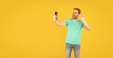 Sarı arka planda telefonla selfie çeken mutlu traşsız genç adam, iletişim..