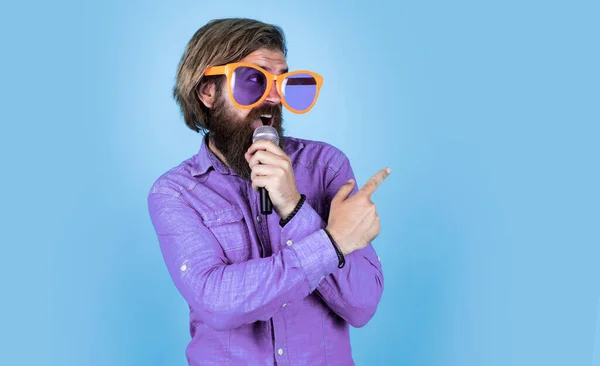 just look at this. vocal school. favorite music style. concept of music. performer having fun. mature bearded man in funny party glasses sing song. brutal male hipster with microphone.