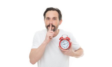 Arka planda çalar saati olan sessiz adam, sessiz ol. Çalar saati olan bir adamın fotoğrafı sessiz bir jest gösteriyor. Çalar saati olan sessiz adam beyaza izole edilmiş. Stüdyoda çalar saati olan sessiz bir adam..