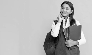 Okul çantalı mutlu bir öğrenci ve sarı arka planda çalışma kitabı var..