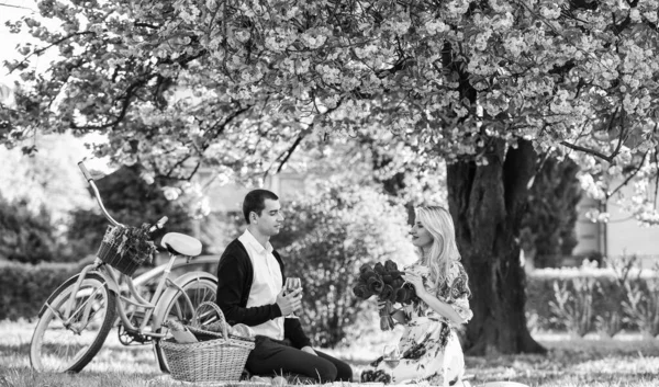 Be happy. retro bicycle. happy couple in love. woman and man lying in park and enjoying day together. valentines day picnic. romantic picnic in park. couple date on blanket under sakura flowers.