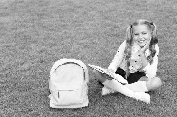 Okul Çantalı Mutlu Çocuk Yeşil Çimlerin Üzerinde Oturmuş Kitap Okuyor — Stok fotoğraf