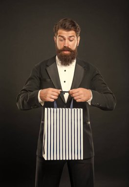 Smokinli, papyonlu, siyah arkaplanlı ve alışveriş çantalı bir adam. Boşluğu kopyala.