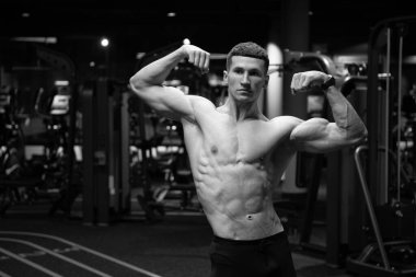 Kaslı gövdeli güçlü bir adam. Kol kasları kaslı. Spor salonunda çift kol kasları var..