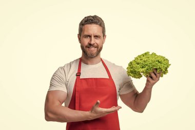 Önlüklü bir adam marul sunuyor..