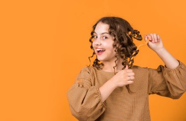 Güzel, sağlıklı saçlar. Parlak buklelerin tadını çıkarıyorum. Şekil vermek için yağ kremi. Kuaför malzemeleri. Moda ve güzellik. Küçük kız kuaför salonu. Küçük kıvırcık saçlı çocuk. Parti için saç stili.