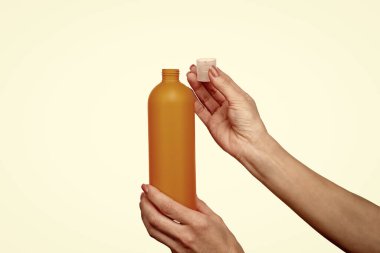 Kadın elleri güneş kremi şişesini fotokopi alanı ile tutuyor..