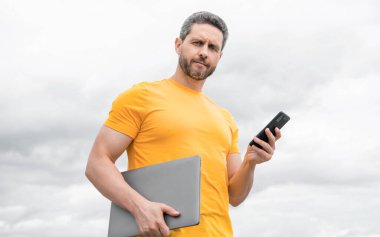 Bilgisayarlı bir adam gökyüzünde akıllı telefondan sohbet ediyor..