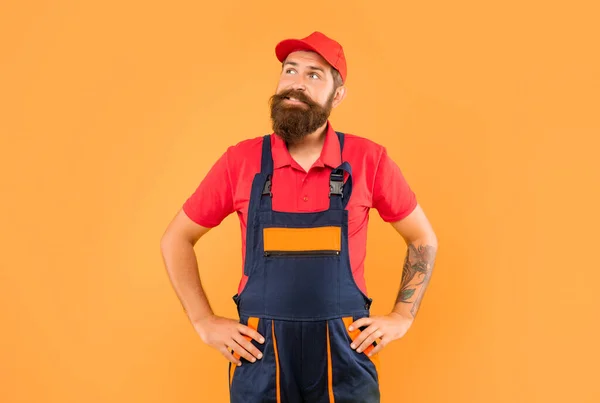 thinking bearded man loader in work clothes on yellow background.