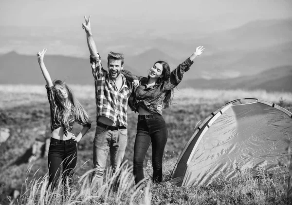 Camping gear. Camping tent. Feel freedom. Happiness concept. Hiking activity. Friends set up tent on top mountain. Camping equipment. Weekend in mountains. Man and girls having fun in nature.