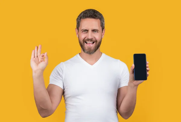 很高兴有人展示了带有复制空间的手机屏幕 显示在黄色背景下隔离的手机屏幕的人 男人显示手机屏幕在工作室 显示手机屏幕的男人 — 图库照片
