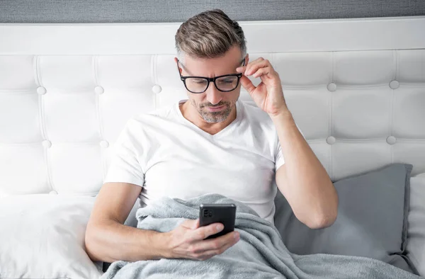 Mature Man Bed Chatting Phone Wearing Eyeglasses —  Fotos de Stock