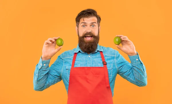 Surprised Man Red Apron Holding Fresh Limes Citrus Fruits Yellow — Stock Fotó