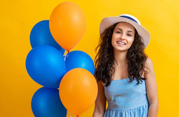 portrait of summer woman with balloons on background. photo of summer woman with balloons wearing hat. summer woman with balloons isolated on yellow. summer woman with balloons in studio.