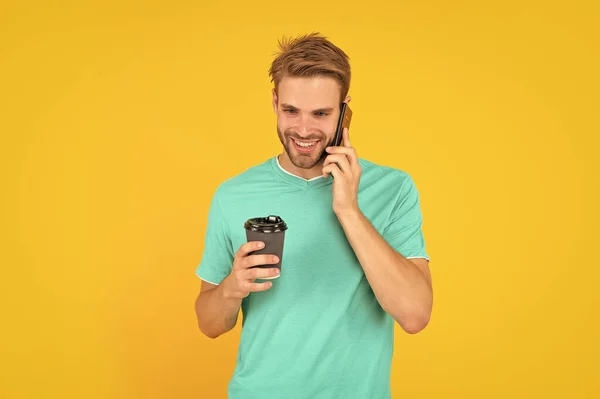 Glad Orakad Ung Man Prata Telefon Med Kaffekopp Gul Bakgrund — Stockfoto