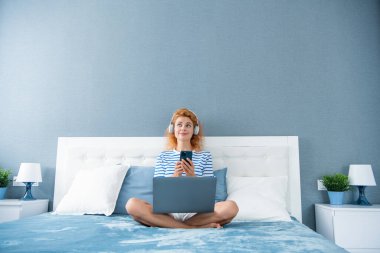 İnternetten alışveriş yapan bir kadın. Kadın gülüşü evde telefonla alışverişe çıkıyor. İnternetten kulaklıklı kadın alışverişi.