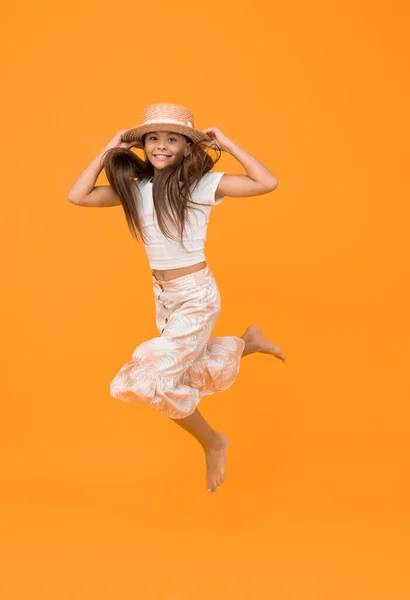 sense of freedom. carefree childhood happiness. small girl wear summer outfit. summer vacation fashion. happy childrens day. having fun on beach party. kid in straw hat. happy barefoot child jump.