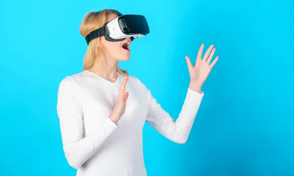 Cheerful smiling woman looking in VR glasses. Confident young woman adjusting her virtual reality headset and smiling. Amazed young woman touching the air during the VR experience