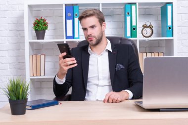 Başarılı bir iş adamı masada mesajlaşıyor. İş adamı telefonda mesajlaşıyor. İş adamı akıllı telefonla mesajlaşıyor. İş adamı mesajlaşmasının fotoğrafı. Ceket giy..