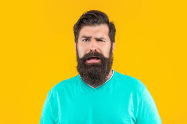 Stüdyodaki kafası karışık sakallı adam. Arka plandaki sakallı adam. Bıyıklı sakallı adamın fotoğrafı. Sakallı adam sarıda izole edilmiş..