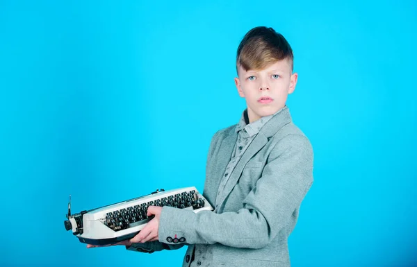 Vintage typography. Cute boy having typing machine. Small kid with vintage typewriter. Smart child using machanical vintage machine. Little boy holding vintage typewriter on blue background.