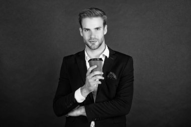 Takım elbiseli girişimci elinde kağıt kahve fincanı tutuyor..