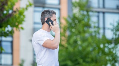 Telefonda konuşan bir adamın görüntüsü. Adamın dışarıda telefonu var. Sokakta telefonla konuşan bir adam var. Dışarıdan bir adam aradı..